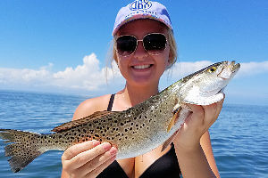 Pretty young lady angler showing off a Speckled Trout she caught.