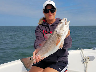 Amy holding up a really nice red drum on her honeymoon.