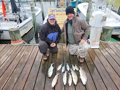 Bill and Cathy Almond kneeling behind their day's catch on the Teach's Lair Dock.