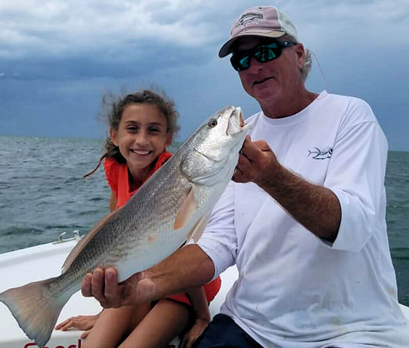 Capt. Rick holds up Red Drum caught by young lady.