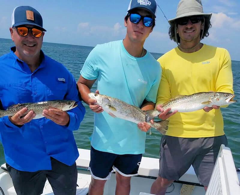 Jason, Nate and Jerd holding their catch of speckled trout.