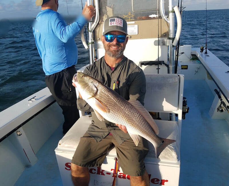Angler onboard boat holding up a nice Red Drum.
