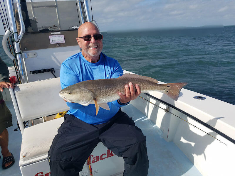 Angler onboard boat holding up a nice Red Drum.