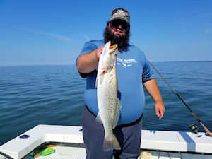 Angler holding up a large Speckled Trout just caught on the Pamlico Sound.